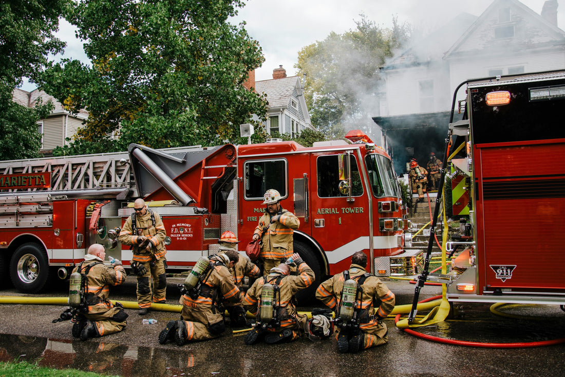 A group of firemen sitting outside a burnt house taking a break after successfully putting out the fire. Tariffs, Small Businesses and Fire Protection Equipment.