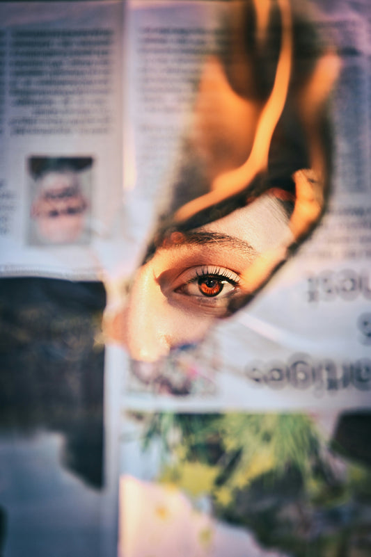 What Is Fire Weather? And Why Every Homeowner Should Be Paying Attention. A Picture showing a newspaper being burnt with a hole in the middle, behind the burnt paper in the hole there is the eye of a woman.