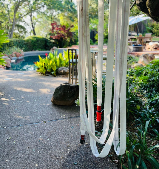 The Hidden Fire Hose in Your Backyard: Real Fires, Real Families, Real Results. A picture showing a FireFighter1 hose hung from a tree in a customer's backyard next to a pool ready to be deployed to fight fires.