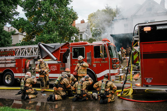 A group of firemen sitting outside a burnt house taking a break after successfully putting out the fire. Tariffs, Small Businesses and Fire Protection Equipment.